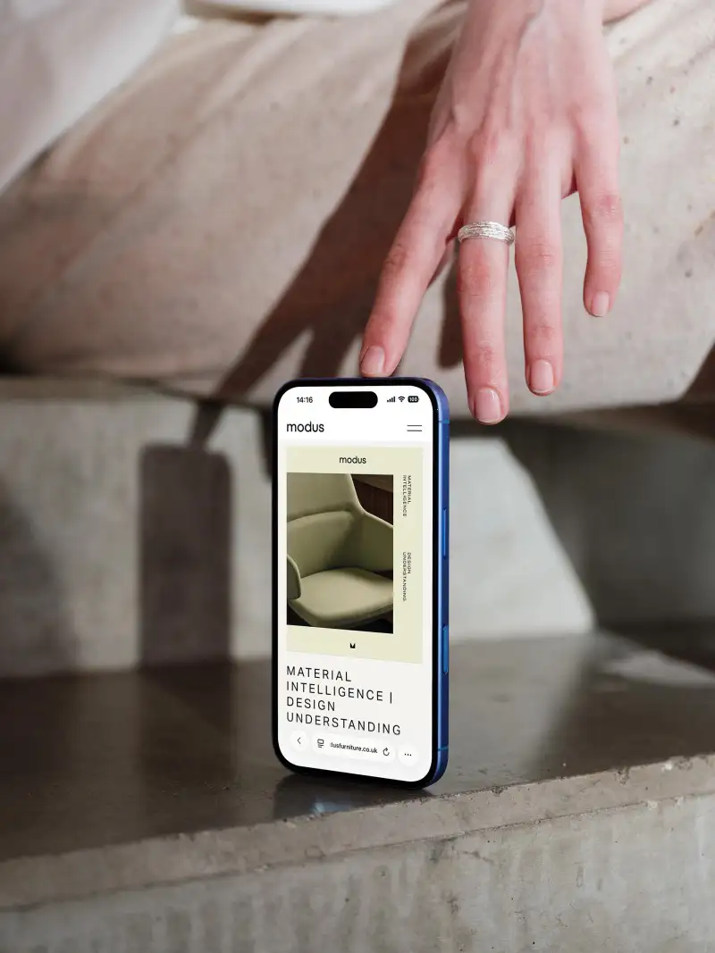 mockuuups iphone 16 mockup on a concrete surface with hand detail