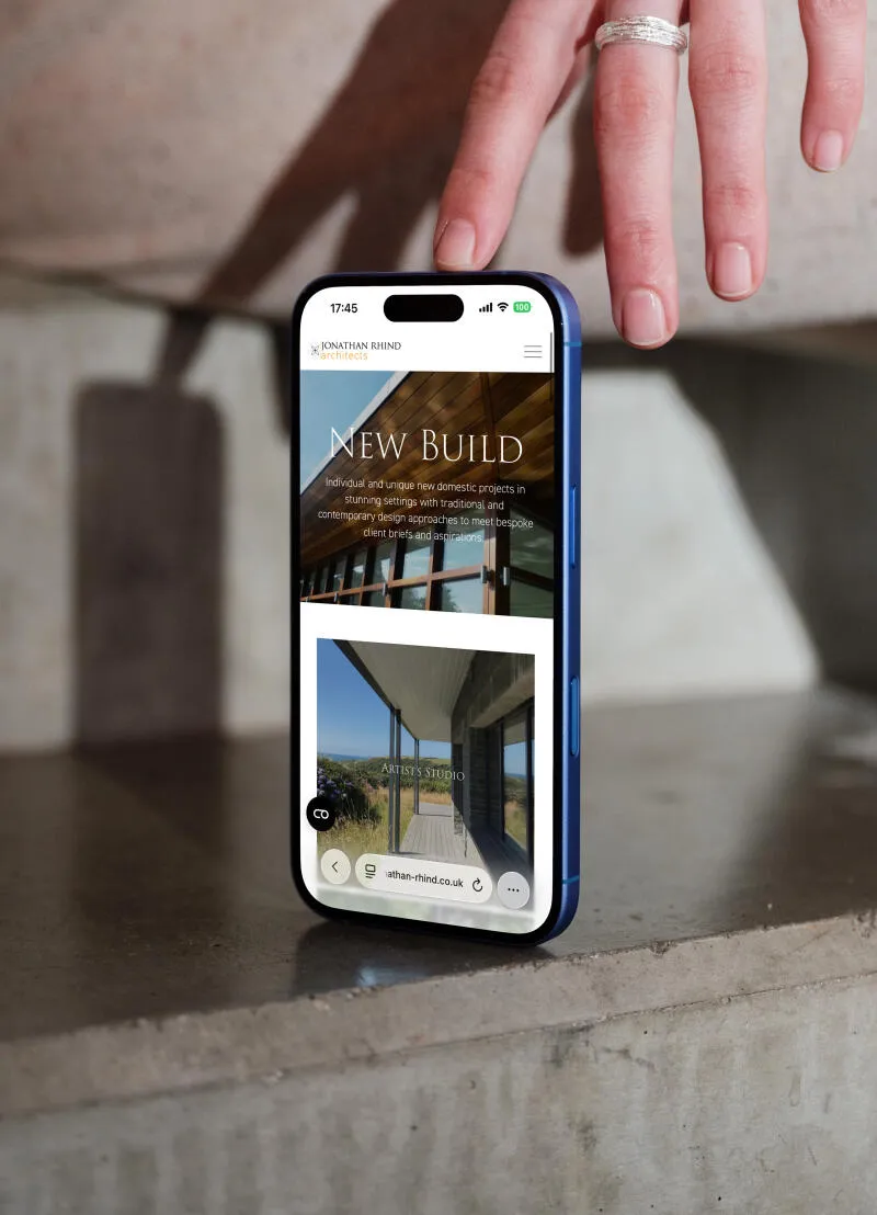 mockuuups iphone 16 mockup on a concrete surface with hand detail