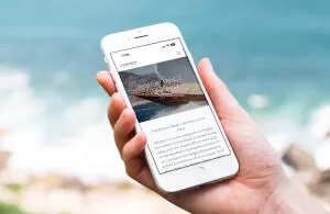 mockuuups holding iphone 7 mockup next to the ocean