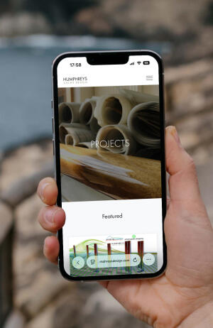 mockuuups iphone 13 pro mockup held up beside the ocean