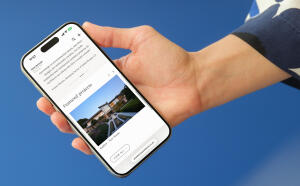 mockuuups iphone 15 pro mockup in a womans hand against a modern blue wall