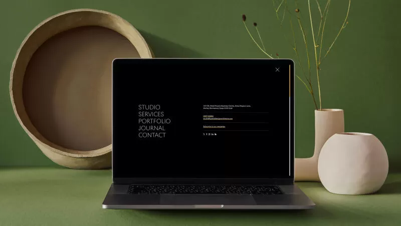 mockuuups macbook mockup on a green slab with flower vase at the side
