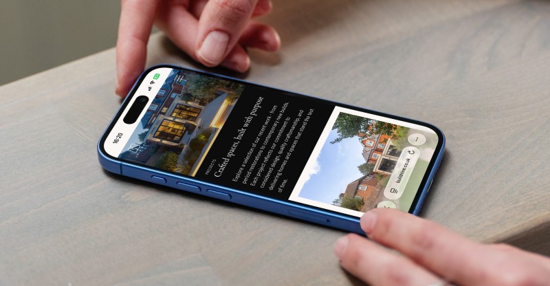 mockuuups iphone 16 mockup on a wooden surface with a hand interacting